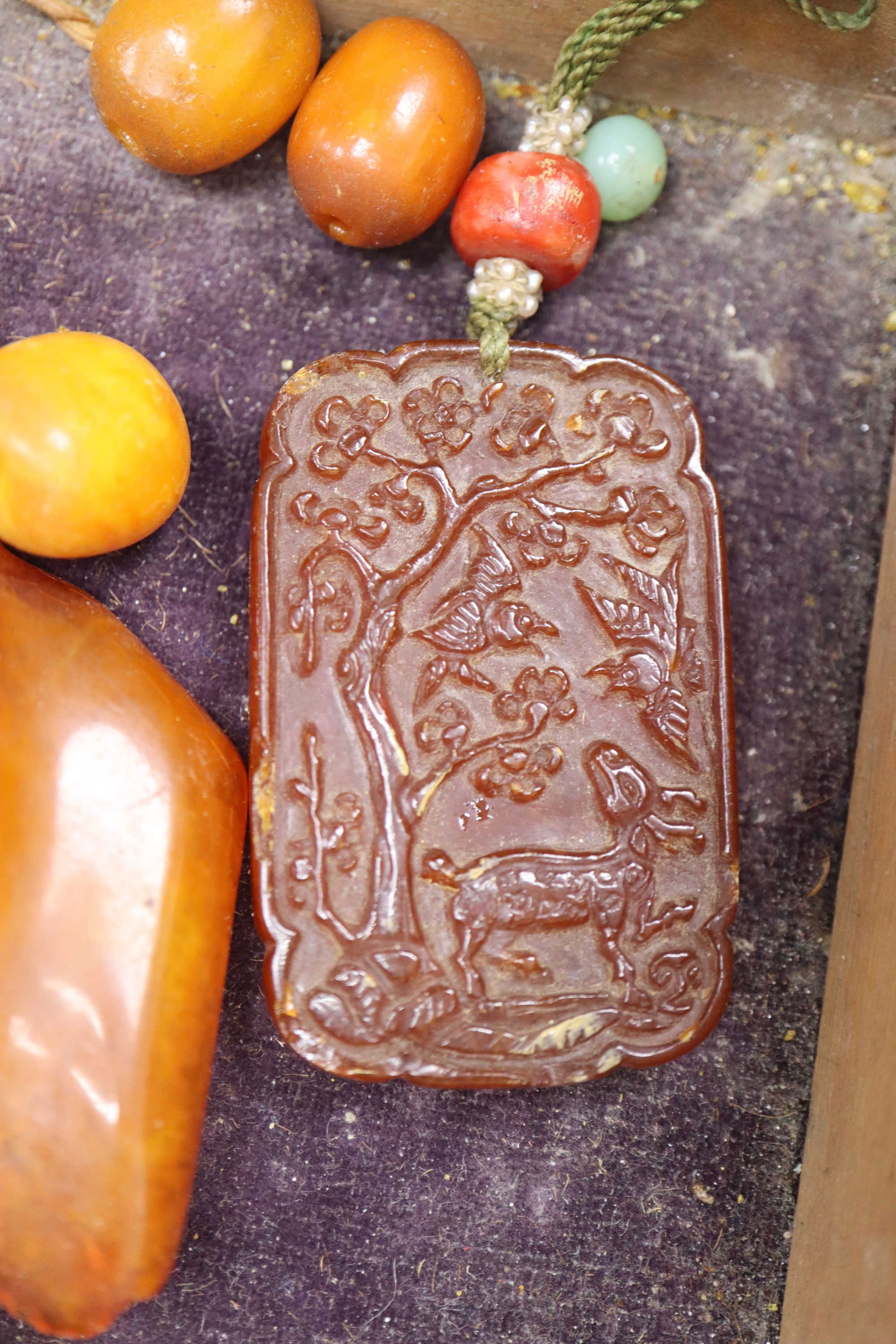 An amber necklace(a.f.) gross 85 grams, four assorted amber pebbles, 528 grams, a carved amber pendant